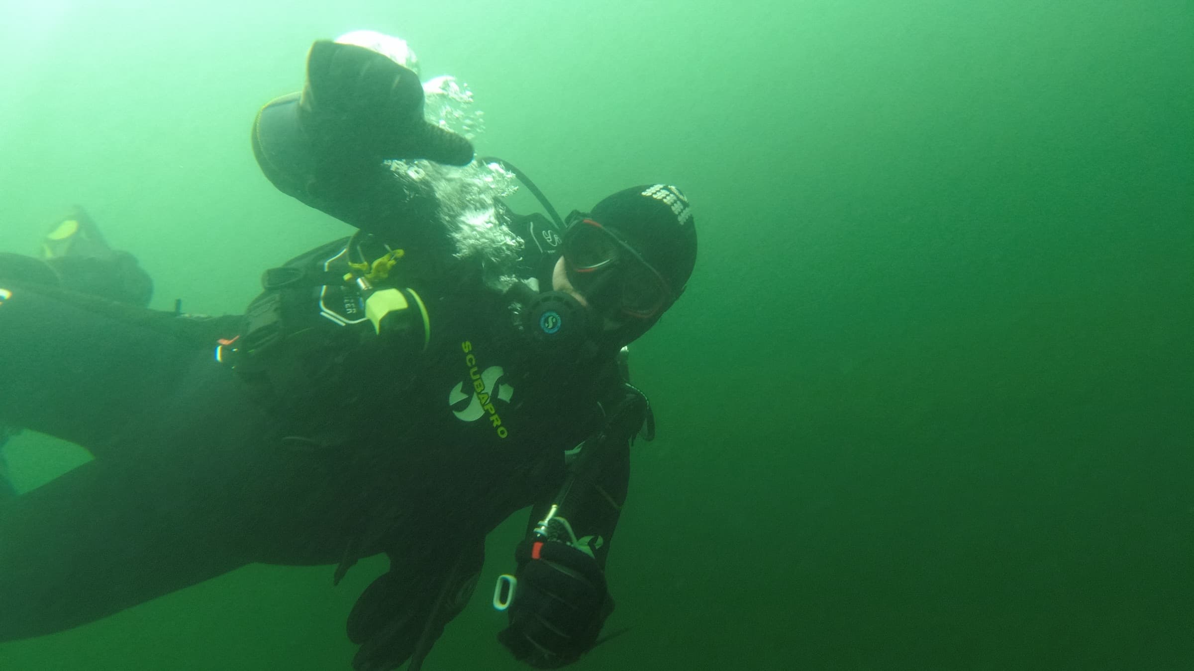 Taucher im grünen Wasser eines Sees, aufgenommen von einem zweiten Taucher aus